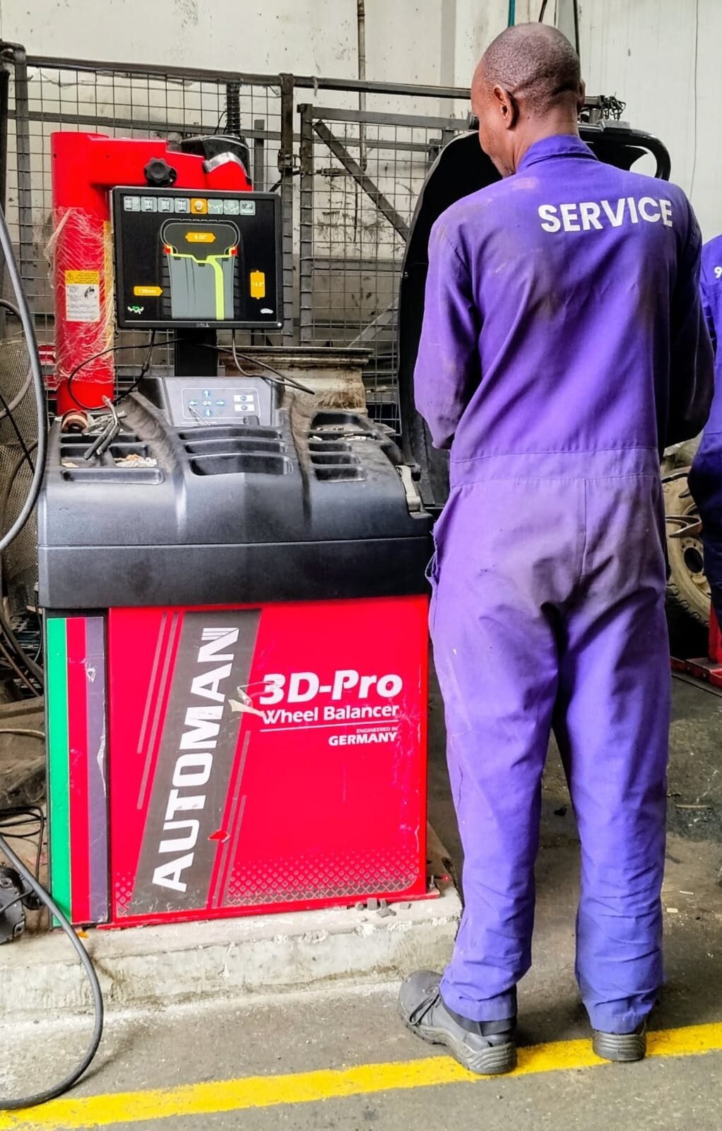 Mechanic checking wheel-balancing machine